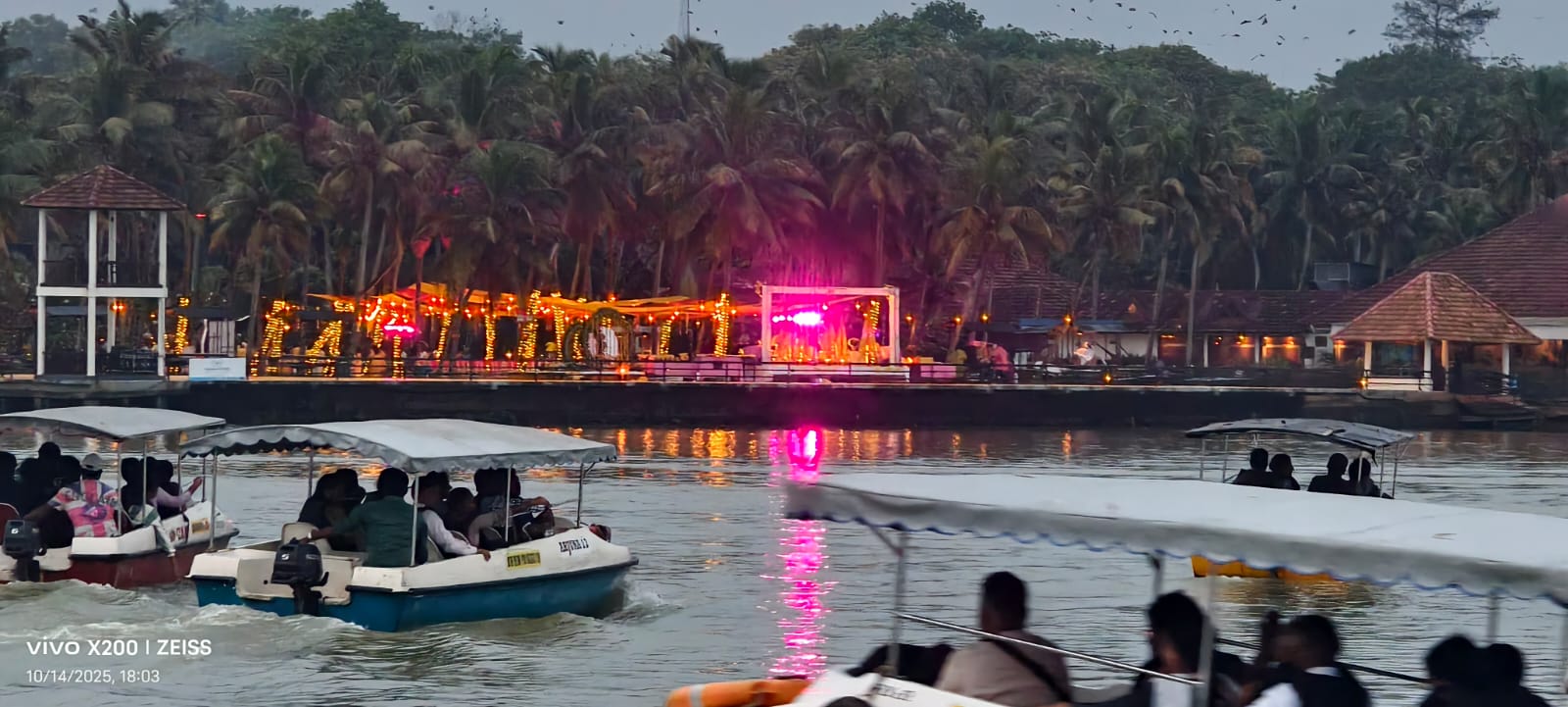 Boats returning past the lit-up waterfront at night